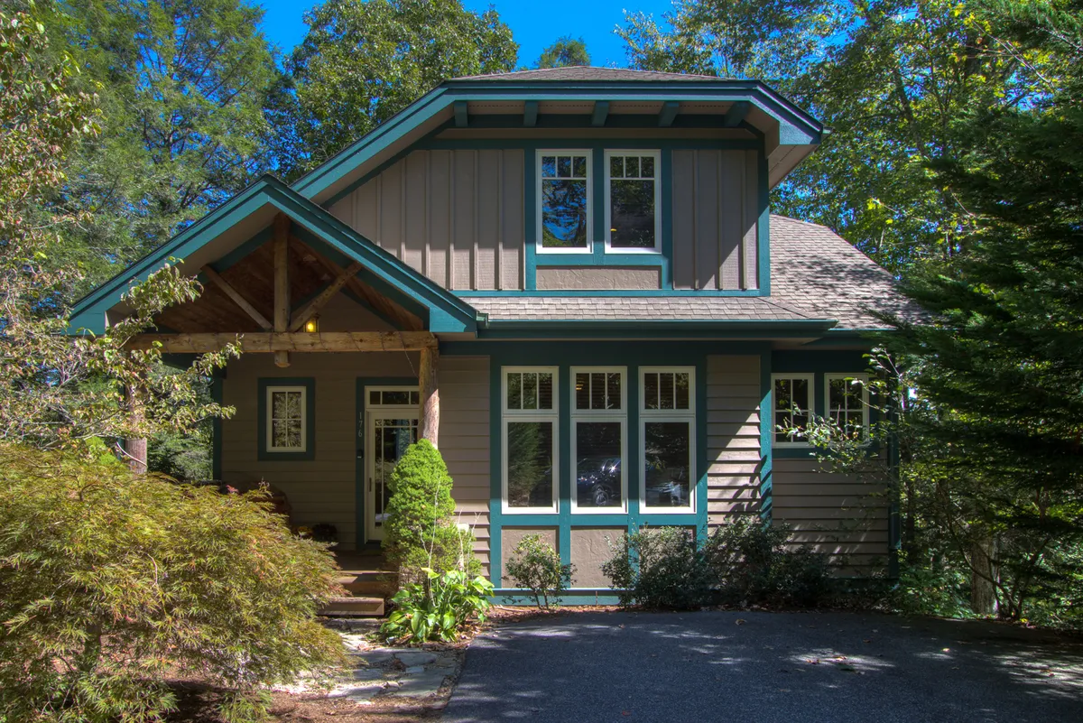 The photo captures a charming front porch with large windows and a beautifully landscaped garden. The setting exudes serenity, offering a glimpse of how guests might start their day with a coffee surrounded by nature or relax after outdoor activities.