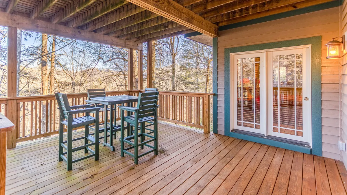 This image shows a spacious wooden deck surrounded by trees, with an outdoor seating area perfect for group gatherings. The serene setting is ideal for relaxing, socializing, or enjoying meals in the fresh mountain air. The natural scenery reinforces the property’s connection to its beautiful surroundings.